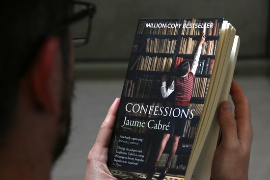 A reader holds an English version of Confessions on January 4 by Cabré (by Violeta Gumà)